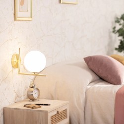 Świecący kinkiet naścienny zamontowany w sypialni koło łóżka