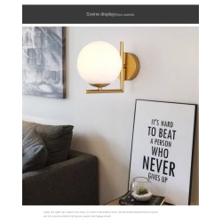 Kinkiet naścienny Złoty Kula Mleczna Riccardo zamontowany na ścianie między obrazami w salonie