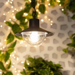 Świecąca Lampa Wisząca z kloszem i żarówką Retro loft Czarna Forte na tle ściany z roślinami